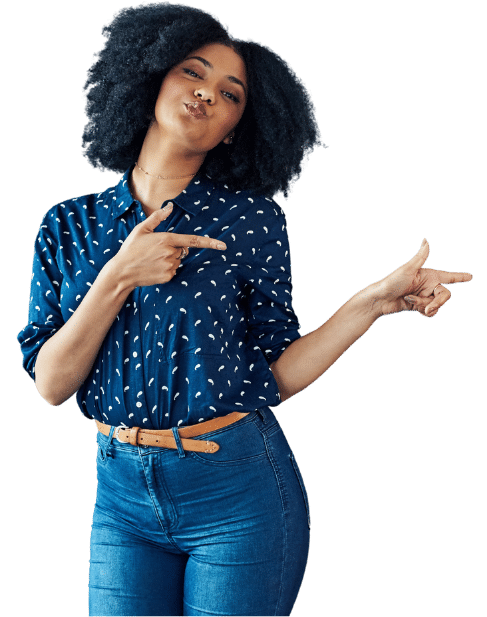 A woman with curly hair wearing a blue shirt with white patterns, pointing with both hands in a cheerful manner.