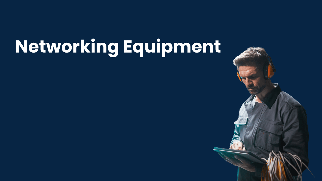 A man wearing headphones, working with networking equipment and a tablet in a dark setting.